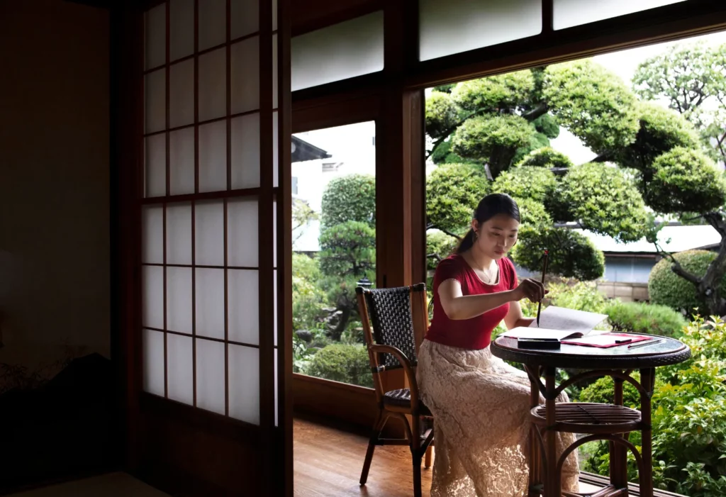 Voyageuse dans une chambre de ryokan ouverte sur un jardin japonais